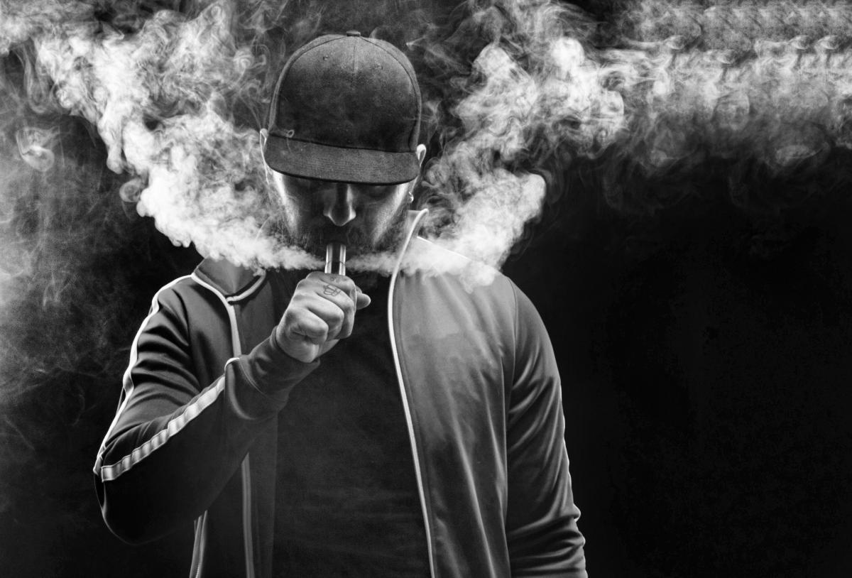 Black and white photo of young man using a vape pen