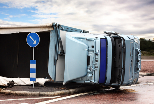 A truck is lying on its side in a car accident on the highway.