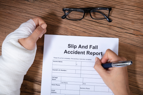 An Overhead View Of Woman With Factured Hand Filling The Slip And Fall Injury Report