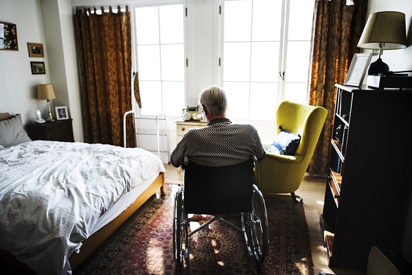 Elderly man, sitting in his wheelchair, alone in his room