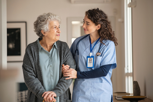 Young caregiver helping senior woman walking.